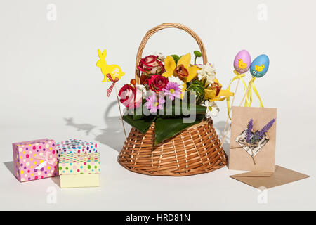 Easter composition. Bright Easter composition of bouquet in basket, colored boxes, cards and eggs. Stock Photo