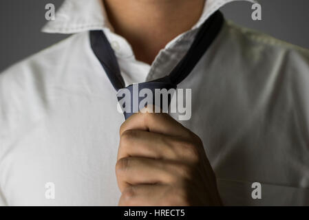 Close up on a man tying a grey necktie