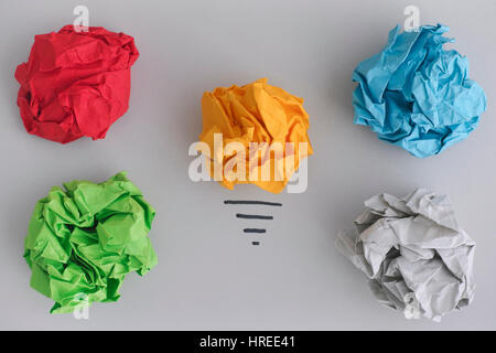 In Search of New Ideas or Innovations. Yellow crumpled paper ball as a light bulb and colorful crumpled paper balls. Stock Photo