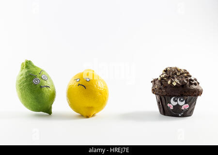 A sweet chocolate muffin and two fresh lemons with cartoon style faces on white background opposing each other Stock Photo