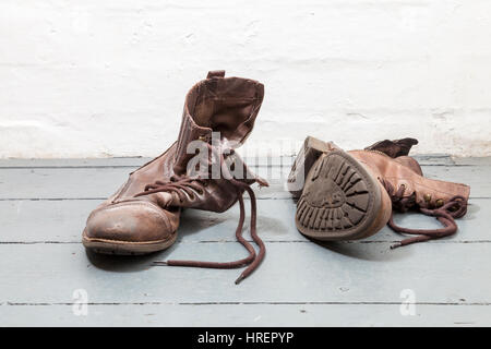 A pair of old brown leather boots left on floorboards Stock Photo