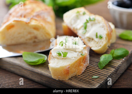 Bread with cheese and a basil leaves on wooden cutting board closeup Stock Photo