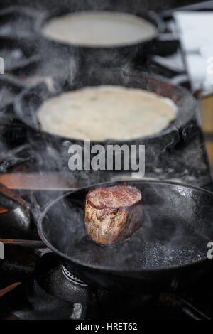 Beef steak fried in pan in restaurant kitchen Stock Photo