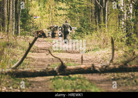 Unidentified Re-enactor Dressed As German Wehrmacht Infantry Soldier In World War II Running Toward A Checkpoint Along A Forest Road. Spring Season Stock Photo