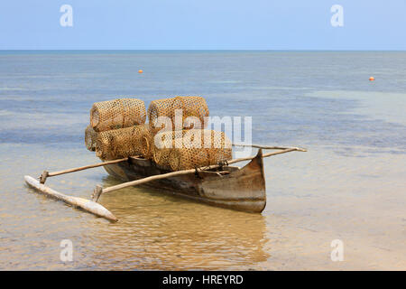 Typical malagasy bamboo woven crustacean fishing trap and catamaran on beach in Nosy Be. Madagascar rural scene. Stock Photo