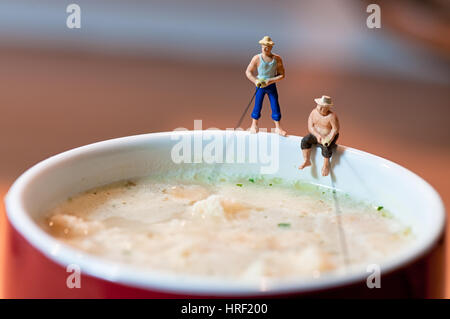 Figurine fishermen fish in a soup mug. Macro photo Stock Photo