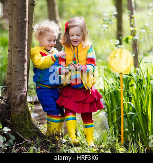 Children playing outdoors. Preschool kids catching frog with net. Boy and girl fishing in forest river. Adventure kindergarten day trip into wild natu Stock Photo