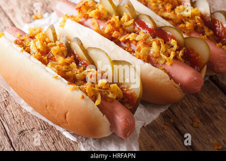 Danish fast food hot dogs with crispy onions, ketchup and pickled cucumbers close-up on the table. horizontal Stock Photo