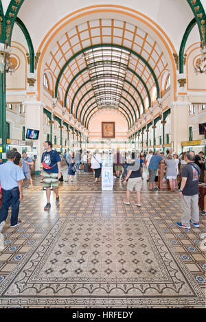 Tourists taking photographs and admiring the colonial architecture inside the Central Post Office of Ho Chi Minh City. Stock Photo