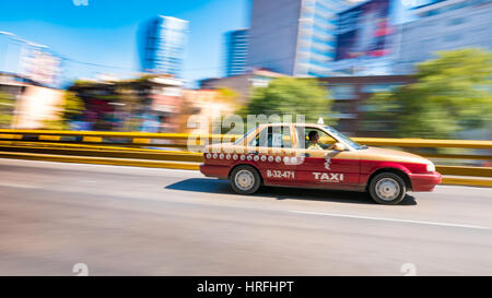 A taxi speeds through the Mexico City landscape, in the sun Stock Photo