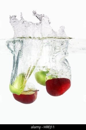 Apples falls deeply under water with a big splash. Stock Photo