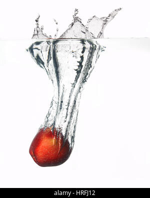 Apple falls deeply under water with a big splash. Stock Photo