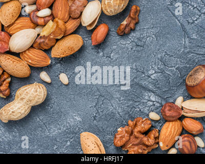 Background of mixed nuts - hazelnuts, walnuts, almonds - on dark concrete background with copy space. Top view or flat lay Stock Photo