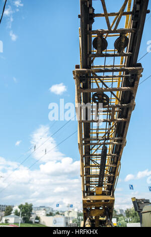 Yellow crane boom with hooks on a city cloud background. Stock Photo