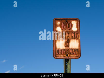 Old vintage metal 'No Parking' sign with blue sky behind. Stock Photo