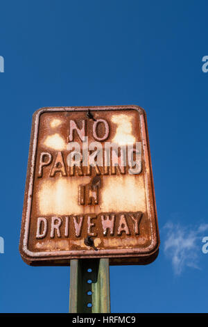 Old vintage metal 'No Parking' sign with blue sky behind. Stock Photo