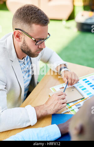 High angle portrait of modern designer focused while thinking about color scheme for his project and drafting sketches Stock Photo