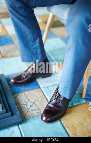 Closeup shot of elegant brown leather men shoes on male legs dressed in blue formal suit Stock Photo