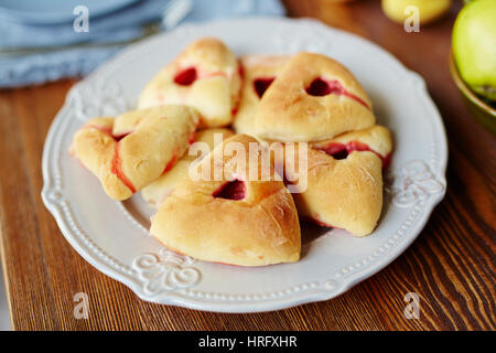 Close-up view of freshly baked triangular raspberry buns lying on white elegant plate Stock Photo