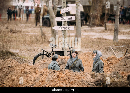 Gomel, Belarus - November 26, 2016: Three Unidentified Women Reenactors Dressed As German Wehrmacht soldiers at World War II sits in trench. Stock Photo