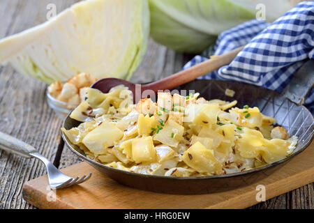 Vegetarian pasta with fried white cabbage and onions, an Austrian specialty called 'Krautfleckerl', served in an iron frying pan Stock Photo