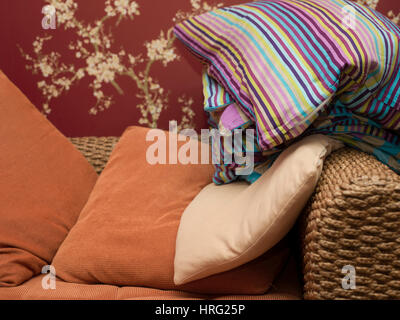 A bunch of colorful pillows on a wicker sofa, cropped interior shot Stock Photo
