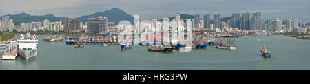 A 4 picture stitch panoramic view of Sanya harbour in China with fishing boats ships moored and the skyscrapers of the city behind. Stock Photo
