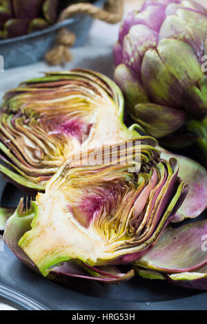 Fresh big Romanesco artichokes green-purple flower heads ready to cook seasonal food Stock Photo