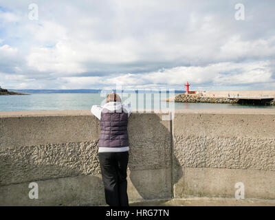 Bangor, Northern, Ireland. 1st March, 2017. UK weather: A woman looks out to Belfast Lough as Bangor enjoyed a generally sunny day although the temperature only reached around 8C. Rain is forecast for this evening with the temperature dropping to 4C. Credit: J Orr/Alamy Live News Stock Photo