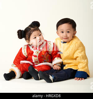 Chinese baby boy and girl in traditional Chinese New Year outfit celebrating Lunar New Year Stock Photo