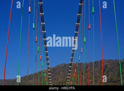 India Uttarakhand State Rishikesh the world capital of Yoga on the banks of the Ganga river Ram Jhula Bridge in blue sky Stock Photo