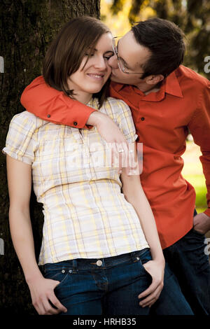 Model released, Junges Liebespaar lehnt an Baumstamm - couple Stock Photo