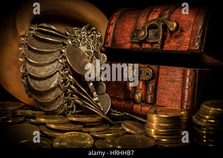 Treasure chest, pile and pillar of coins, and a ceramic bowl filled with jewelry coins in dark environment Stock Photo