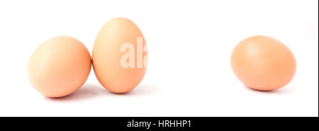 Two upright chicken eggs and one laying sideways isolated on white. Stock Photo