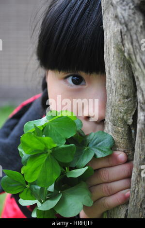 Shy Girl Behind a Tree Playing Hide and Seek Stock Photo