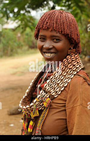 DIMEKA, OMO VALLEY, ETHIOPIA - JULY 27: Portrait of the woman from Hamer people resting by the fence in transit to the local marketplace in Dimeka, Om Stock Photo