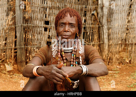 DIMEKA, OMO VALLEY, ETHIOPIA - JULY 27: Portrait of the woman from Hamer people resting by the fence in transit to the local marketplace in Dimeka, Om Stock Photo