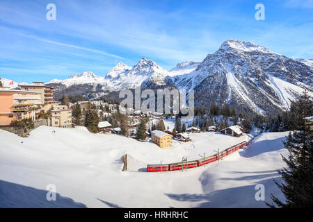 Red train of Rhaetian Railway passes in the snowy landscape of Arosa, district of Plessur, Canton of Graubunden, Switzerland Stock Photo