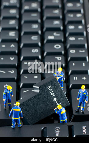 Team of construction workers working with ENTER button on a computer keyboard Stock Photo