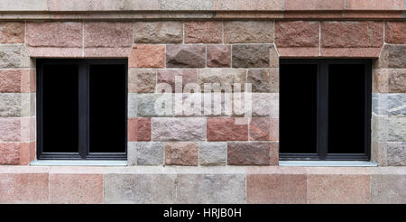 In a building wall from large red granite blocks there is a two windows. Glass isolated on black  with patch Stock Photo