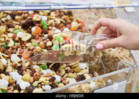 Buyer with scoop takes mixture of nuts and candied fruit in the store Stock Photo