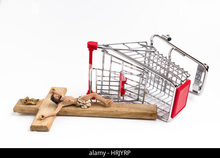 Shopping cart overturned with crucifix on the ground. Conceptual representation of commodification of religion, loss of faith, blasphemy. Stock Photo