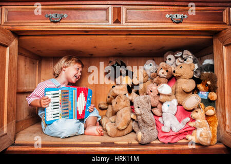 Five year old girl playing accordion for her stuffed animals, Tyrol, Austria Stock Photo