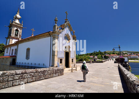 Portugal: Woman with backpack walking along roman bridge and medieval chapel in St. James Way stop Ponte de Lima Stock Photo