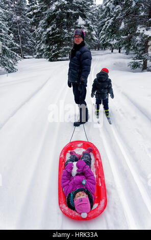 A little girl (2 yrs old) being pulled by her mother in a sledge Stock Photo