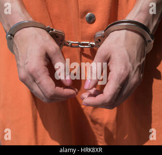 Woman wearing handcuffs and  orange prison jumpsuit Stock Photo
