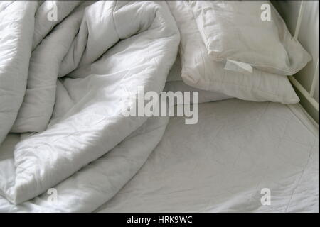 Duvet and pillows on an unmade bed Stock Photo