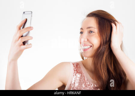 Young woman using her smart phone to shoot a selfie and smiling. Stock Photo