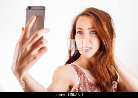 Young woman using her smart phone to shoot a selfie and smiling. Stock Photo