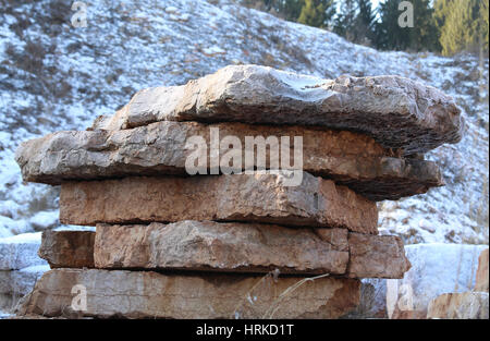 large marble quarry without people with the red marble blocks extracted from the mountain in winter with snow Stock Photo